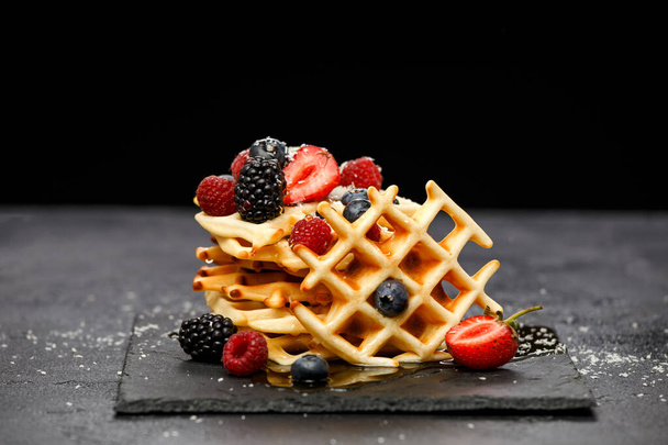 Photo of viennese wafers with berries pouring honey on black background in studio - Photo, Image