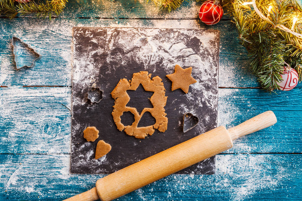Фото соснових гілок, тіста, форми для печива, прокатний штифт на синьому дерев'яному фоні
 - Фото, зображення