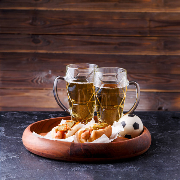 Картина двох чашок пива та хот-догів на дерев'яному фоні
 - Фото, зображення