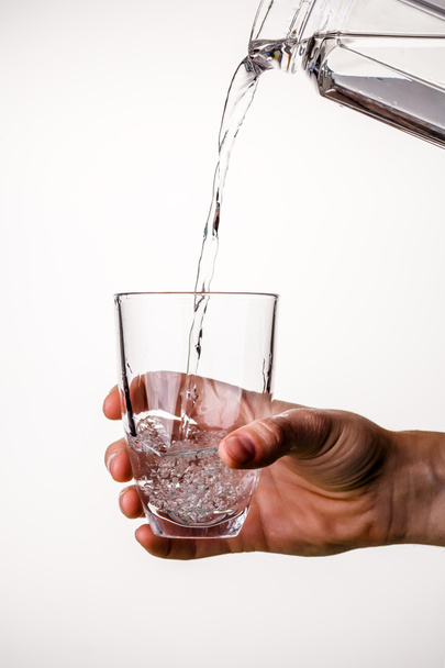 Kuva veden kaatamisesta kannusta lasiin tyhjällä pohjalla
 - Valokuva, kuva