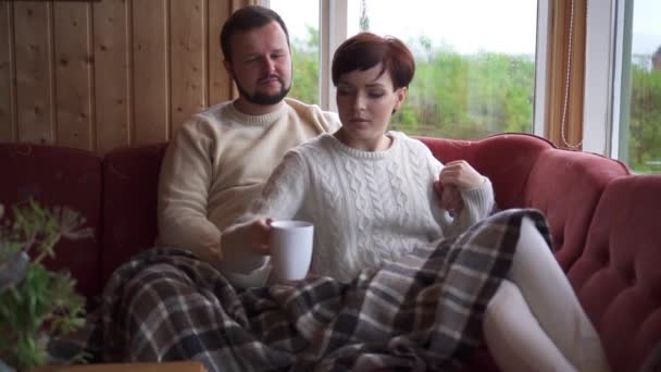 Couple sitting and hugging on sofa at home - Materiał filmowy, wideo
