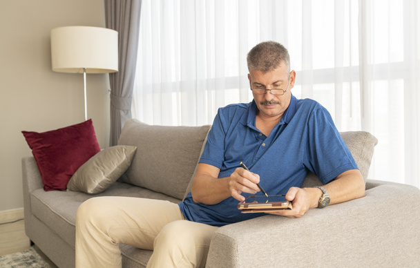 homme d'âge moyen travaillant sur sa tablette sur un canapé
 - Photo, image
