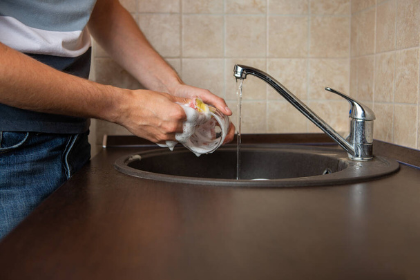 Kuva puolella miehen kädet pesu läpinäkyvä muki pesuallas keittiössä
 - Valokuva, kuva