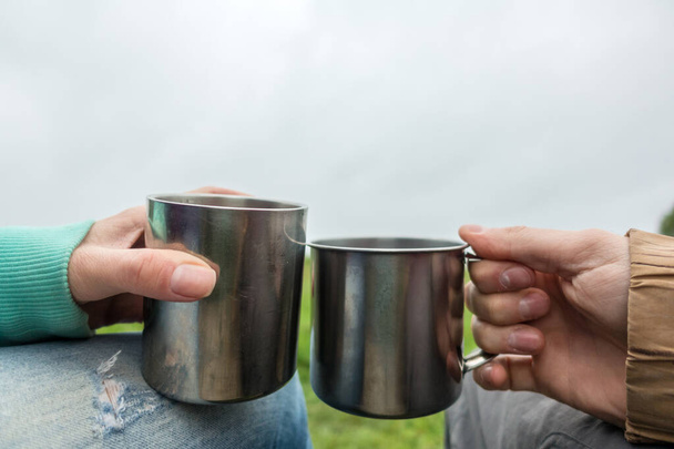 People keep two tourist mugs on picnic by day - Foto, Bild