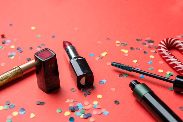 Picture of cosmetics, confetti, christmas decoration on red table - 写真・画像