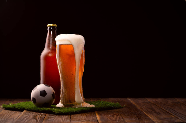 Fénykép Buttle és üveg sör, focilabda zöld fű az asztalnál - Fotó, kép