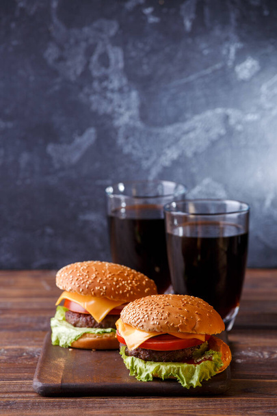 Image of two fresh hamburgers and two glasses of juice on wooden board - Photo, Image