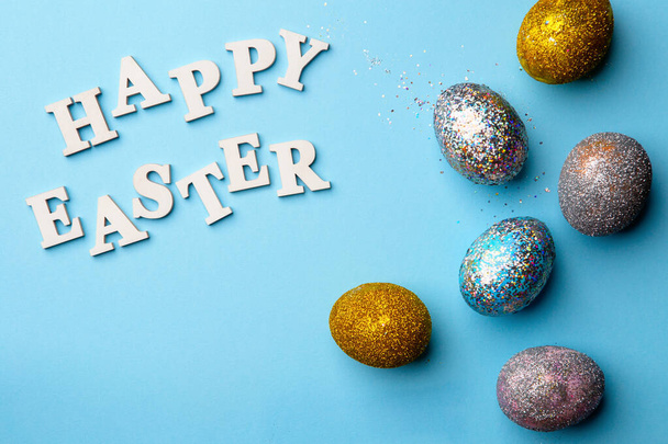 Lettering Happy Easter with eggs on blue background. - Photo, Image