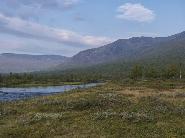 Beautiful wild Lapland nature landscape with blue Tjaktjajakka river, Kaitumjaure, birch tree forest and mountain Sanjartjakka. Northern Sweden summer at Kungsleden hiking trail. Blue sky background - 写真・画像