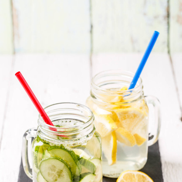 zwei Becher mit infundierter Detox-Diät erfrischendes Wasser: mit Gurke und Zitrone auf weißem Holztisch - Foto, Bild