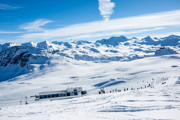 Foto de esquiadores lejanos en estación nevada en invierno por la tarde
 - Foto, imagen