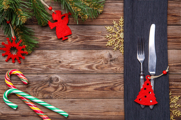 Christmas table place setting with fork and knife, decorated christmas toy - red fir-tree, christmas pine branches and two lollipop cane. Christmas holidays background. - Foto, Imagem