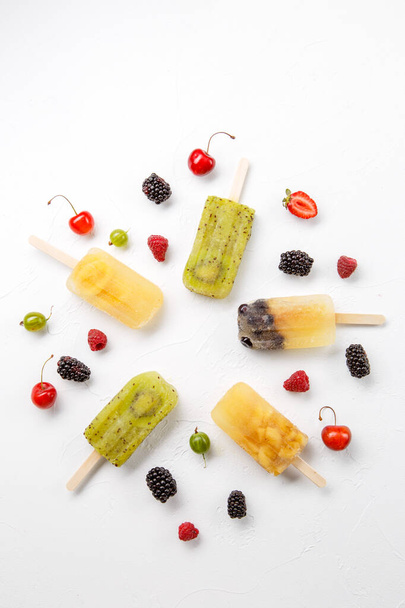 Image from above of frozen fruit juice, gooseberry, blackberry, cherry on white background white background - Photo, Image