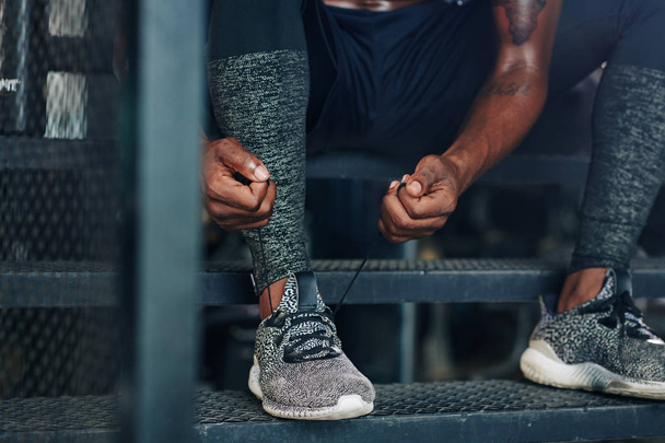 Крупним планом образ спортсмена зав'язування шнурків його спортивного взуття перед тренуванням у спортзалі
 - Фото, зображення