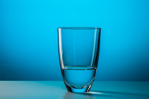 Полное стекло с водой на синем фоне, фото в студии
 - Фото, изображение