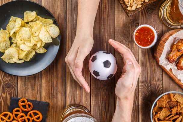 Photo on top of table with snacks, hands with asoccer ball - Photo, Image