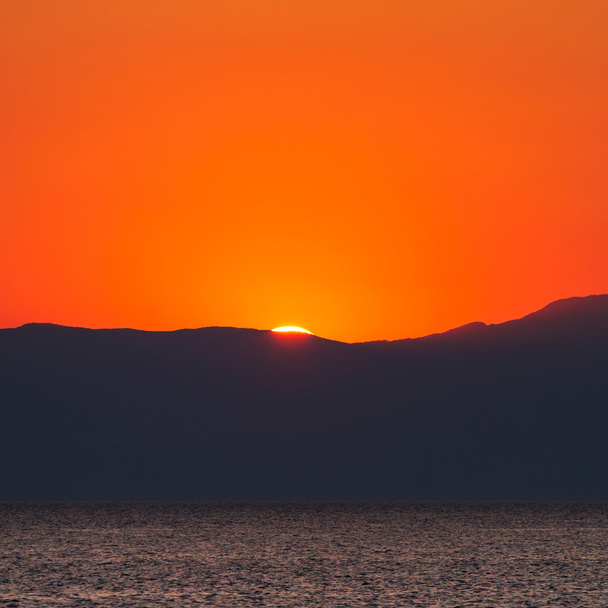 zachód słońca z pięknym widokiem na morze. przesunięcie w dół góry słońce. - Zdjęcie, obraz