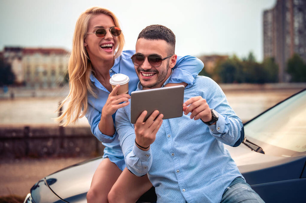 Vacaciones de verano, citas, amor y concepto de turismo - pareja sonriente con tableta al aire libre
. - Foto, Imagen