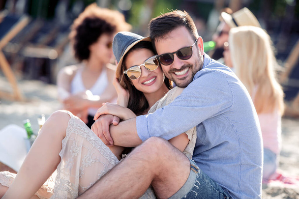 楽しんで幸せな若いカップルはビーチでピクニックし、夏休みに楽しい時間を過ごす. - 写真・画像