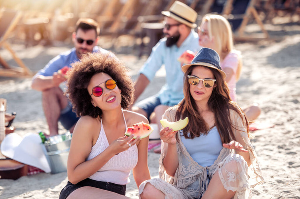 Vrienden die zich vermaken op het strand, watermeloen eten. - Foto, afbeelding