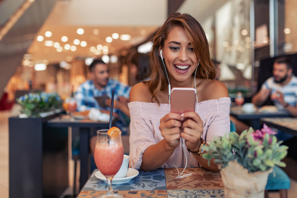 Porträt eines schönen Mädchens mit ihrem Smartphone im Café. - Foto, Bild