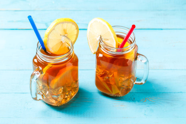 Ledový čaj ve skleněné sklenici s citrónem na modrém dřevěném pozadí. - Fotografie, Obrázek