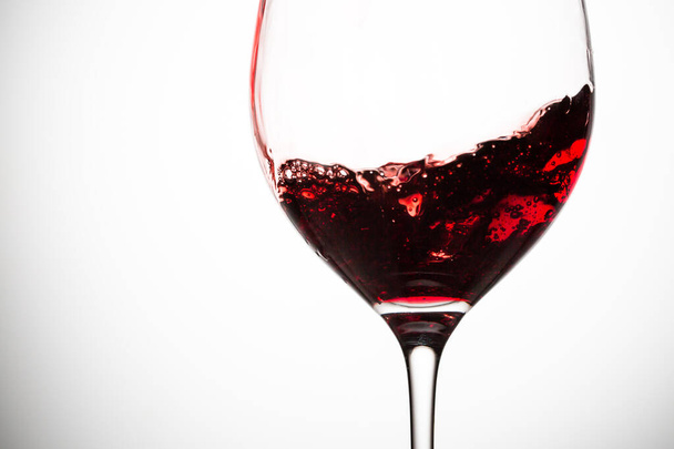 Red wine in wineglass on grey background. Closeup. - Foto, afbeelding
