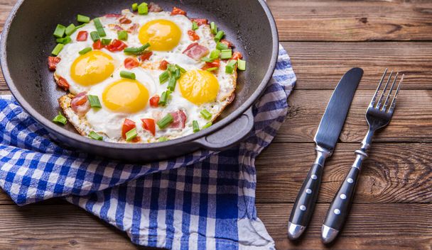 Eier in der Pfanne mit Tomaten und grünen frischen Zwiebeln. Frühstück. gesunde Ernährung. - Foto, Bild