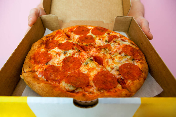 Kuva pizza ruutuun ja kuriiri kädet tyhjä vaaleanpunainen tausta
 - Valokuva, kuva
