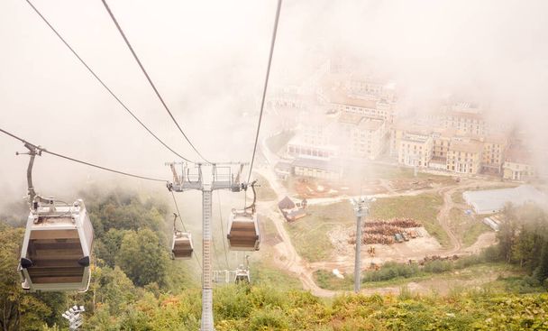日中の霧の空を背景に山の中のケーブルカーの写真 - 写真・画像