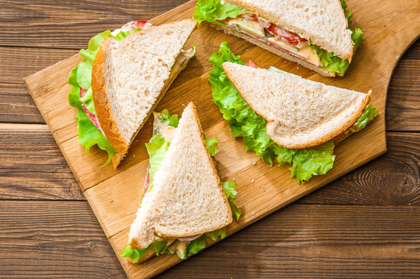 Foto bovenop sandwiches met salade en worst op houten bord - Foto, afbeelding