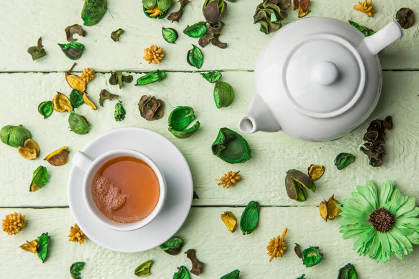 Beyaz çaydanlık ve çay yeşil masa süslemeli kurumuş çiçekler. - Fotoğraf, Görsel