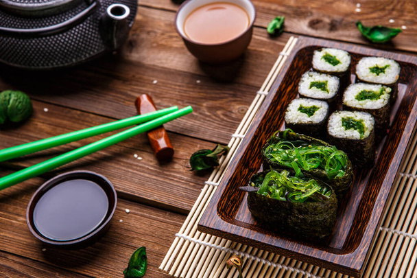 Επιφάνεια φωτογραφίας με σουσάμι, ρολά, σάλτσα, chopsticks - Φωτογραφία, εικόνα