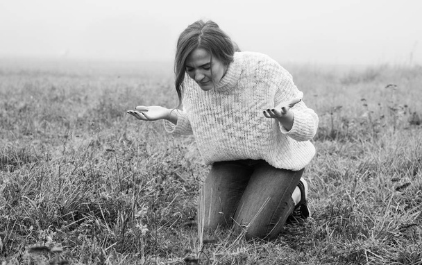 Κορίτσι έκλεισε τα μάτια της στα γόνατα, προσεύχεται σε ένα χωράφι κατά τη διάρκεια της όμορφης ομίχλης.  - Φωτογραφία, εικόνα