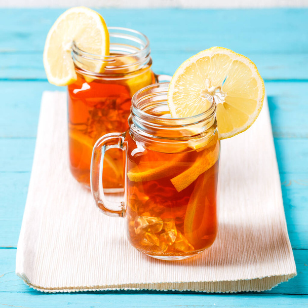 Чай з льодом у скляній банці з лимоном на синьому дерев'яному фоні
. - Фото, зображення