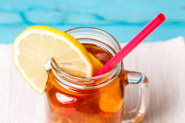 Чай з льодом у скляній банці з лимоном на синьому дерев'яному фоні
. - Фото, зображення