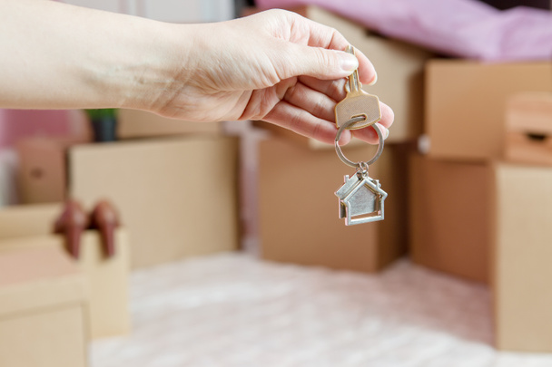 Photo of cardboard boxes, man's hand with keychain, open door in new apartment. Blurred Background - Photo, Image