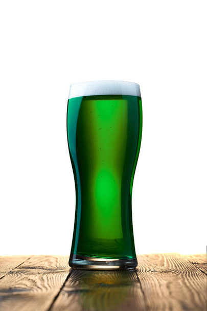 Egy pohár friss hideg zöld sör egy fa asztalon. Elszigetelve. Fogantatás Szent Patrik napjára. - Fotó, kép
