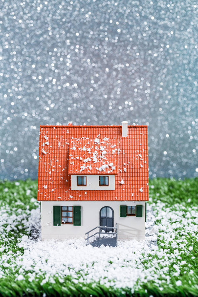灰色の背景に雪が降るおもちゃの家の写真 - 写真・画像