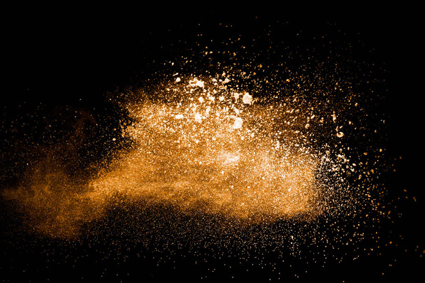 abstract orange powder explosion on black background. Freeze motion of orange dust splash. Painted Holi powder. - Photo, Image
