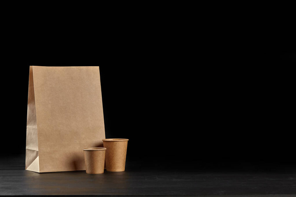 Eco friendly disposable tableware standing on dark surface against black background. Biodegradable craft dishes. Recycling concept. Close-up shot. - Valokuva, kuva