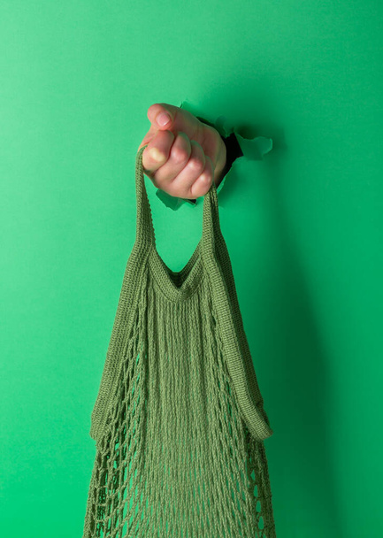 A woman holds reusable Cotton String Portable Shopping Handbag, green background - Photo, Image