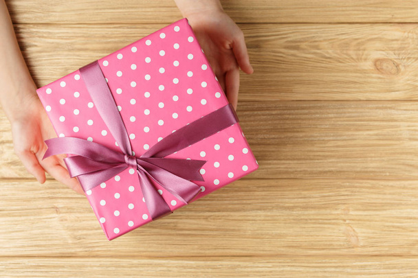 gift box in the hands on a wooden background top view - Фото, изображение