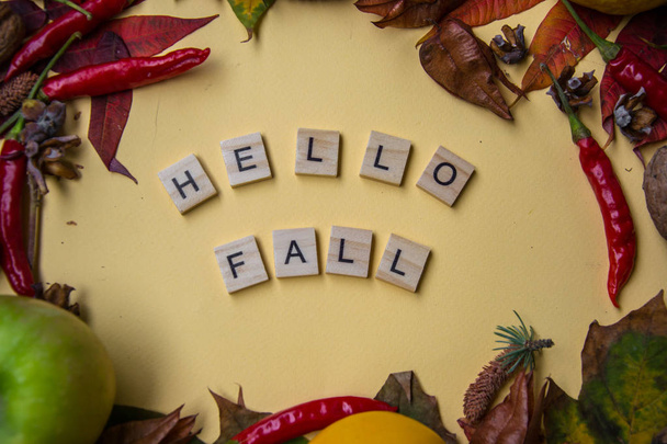Text spelt with wooden letter tiles on pale yellow background, words HELLO FALL, autumn still life, lettering concept - Foto, Imagen