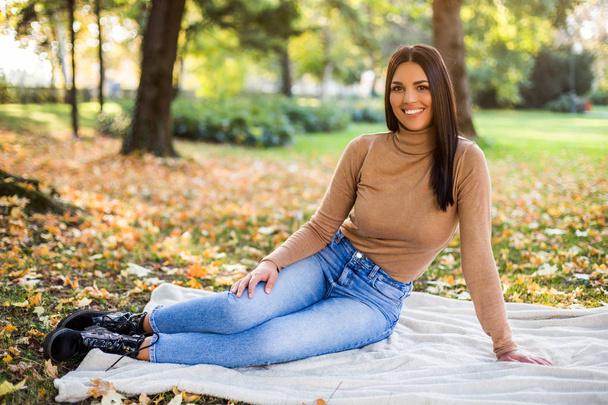 Güzel kadın sonbaharda parkta dinlenirken eğleniyor.. - Fotoğraf, Görsel