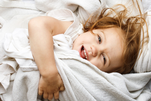 Feliz niño pequeño rodando en cubiertas blancas
 - Foto, Imagen