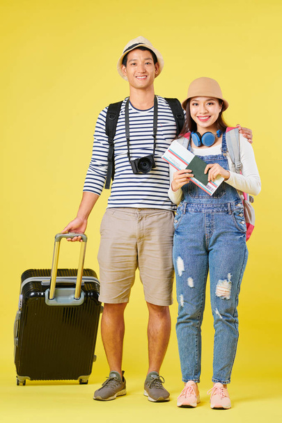 Ευτυχισμένοι νέοι Ασιάτες ταξιδιώτες με μεγάλη βαλίτσα, ψηφιακή φωτογραφική μηχανή, διαβατήριο και αεροπορικό εισιτήριο - Φωτογραφία, εικόνα