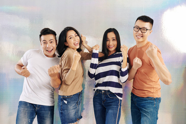 Grupo de jovens asiáticos alegres em roupas casuais dançando e celebrando o sucesso
 - Foto, Imagem
