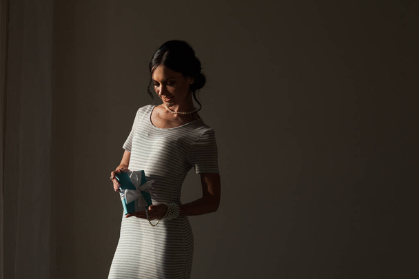 Portrait of a beautiful brunette woman in a dress with gift - Foto, Bild