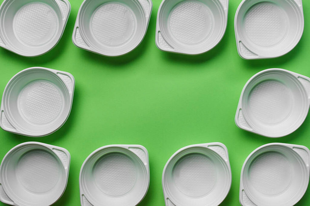 White plastic disposable tableware on green background with copy space. The concept of picnic utensil. Top view. Selective focus. Close-up. - Photo, image